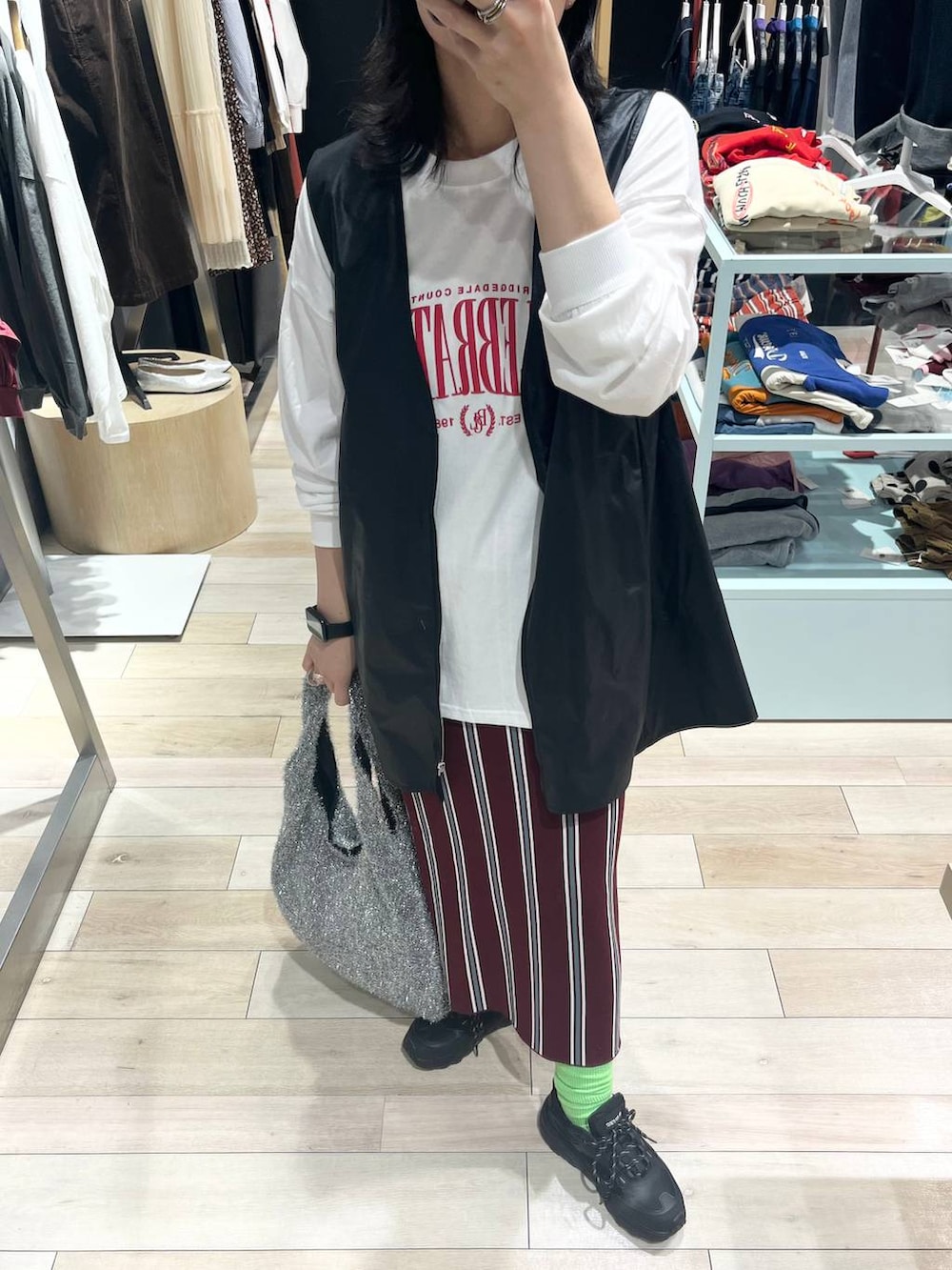 シルバー系のショルダーバッグ、レッド系のスカート、ブラック系のワンピースを着用したレディースの秋コーディネートの8枚目の写真