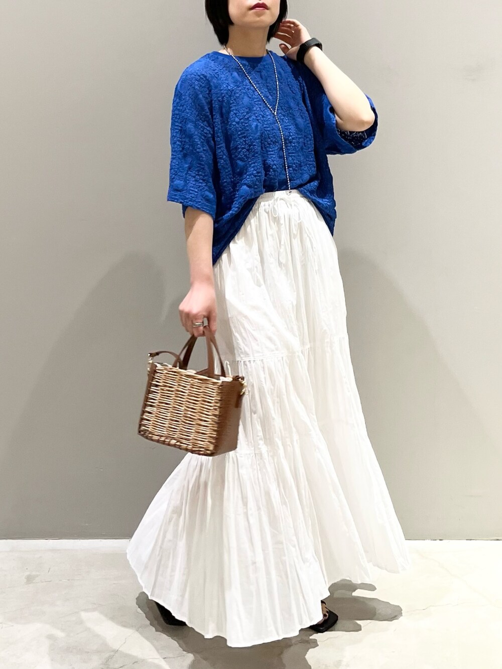 ブラック系のサンダル、ブラウン系のショルダーバッグ、ホワイト系のスカートを着用したレディースの夏コーディネートの9枚目の写真