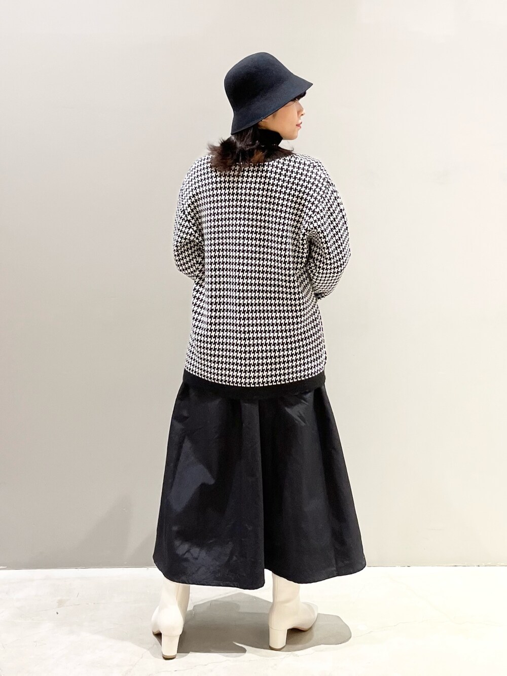 ベージュ系のショルダーバッグ、ホワイト系のブーツ、ブラック系のワンピースを着用したレディースの冬コーディネートの3枚目の写真