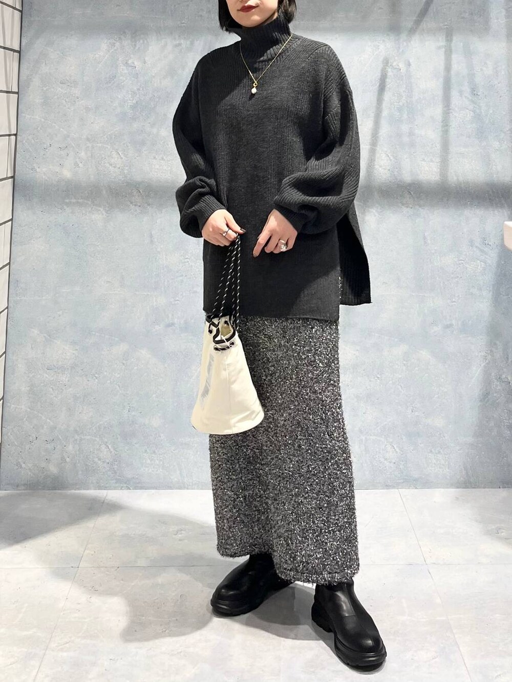 グレー系のTシャツ/カットソー、ブラック系のブーツ、ブラック系のスカートを着用したレディースの冬コーディネートの3枚目の写真