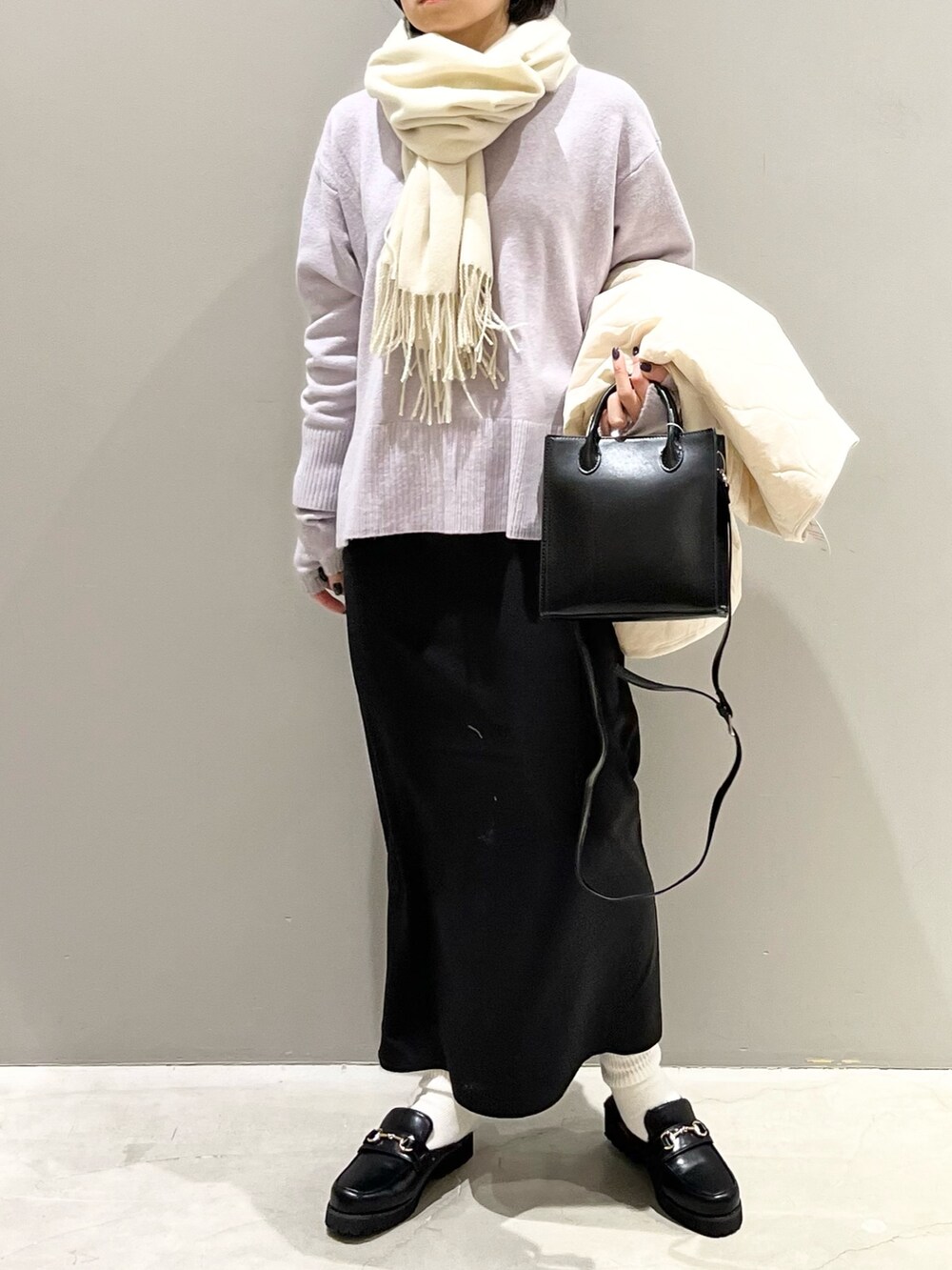 ブラック系のスカート、ブラック系のショルダーバッグ、ブラック系のローファーを着用したレディースの冬コーディネートの2枚目の写真