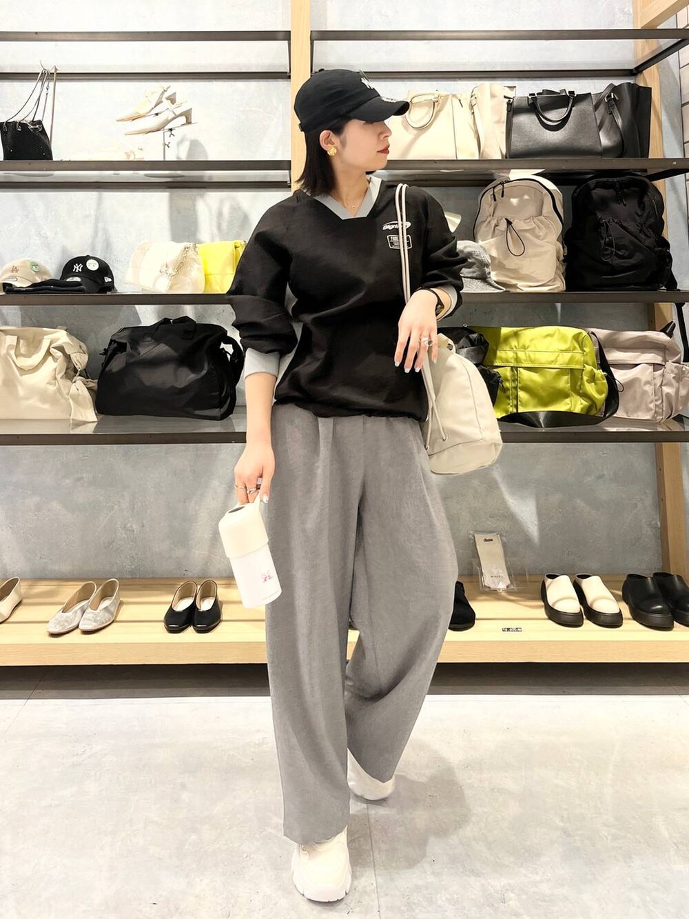 ホワイト系のスニーカー、ベージュ系のショルダーバッグ、グレー系のスラックスを着用したレディースの春コーディネートの2枚目の写真