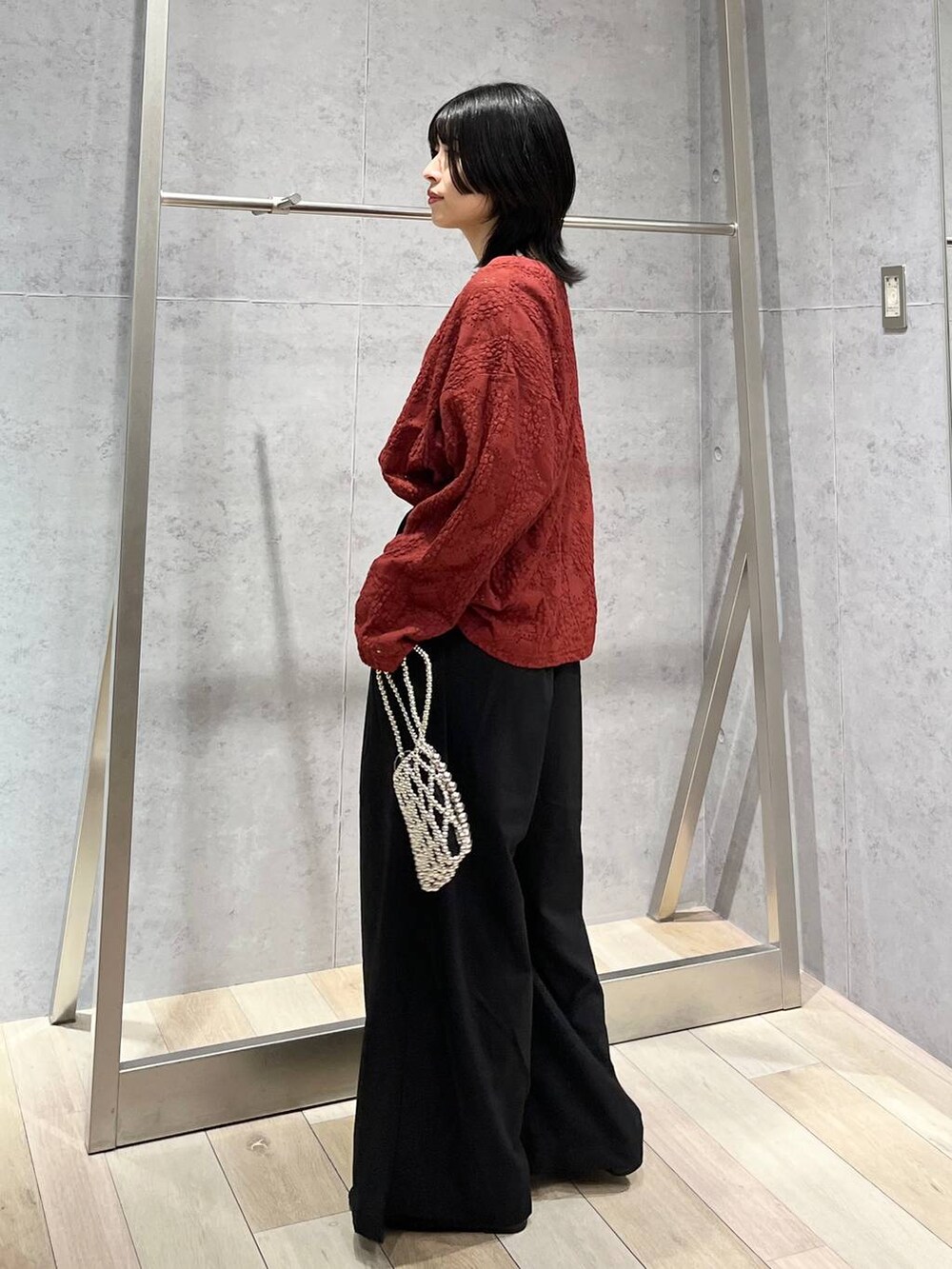 レッド系のTシャツ/カットソー、ブラック系のスラックス、シルバー系のショルダーバッグを着用したレディースの夏コーディネートの4枚目の写真