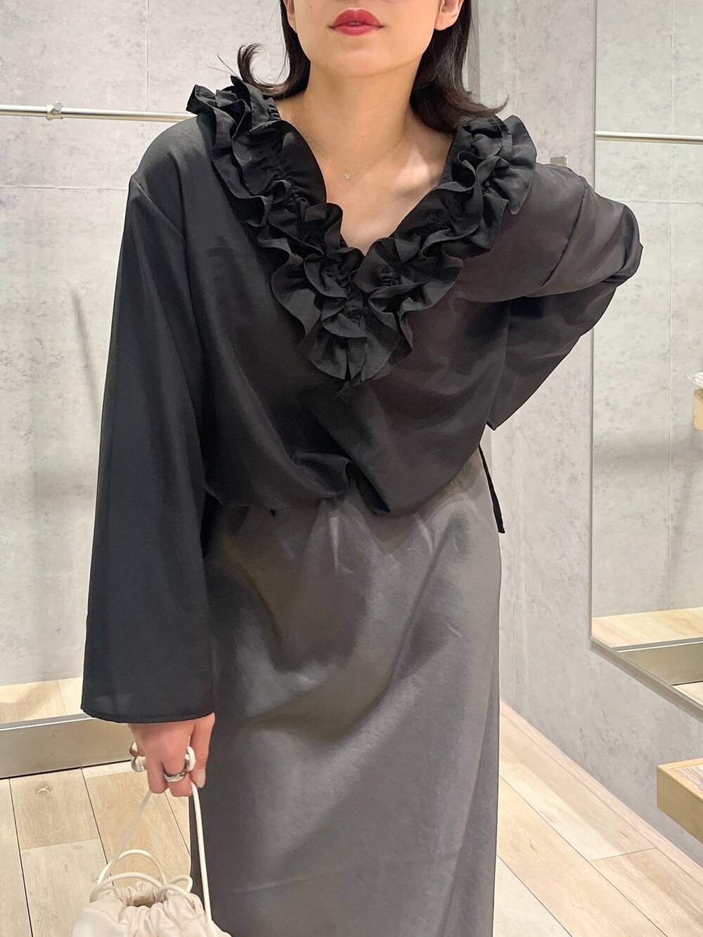 グレー系のスカート、ホワイト系のショルダーバッグ、ブラック系のキャップを着用したレディースの春コーディネートの2枚目の写真