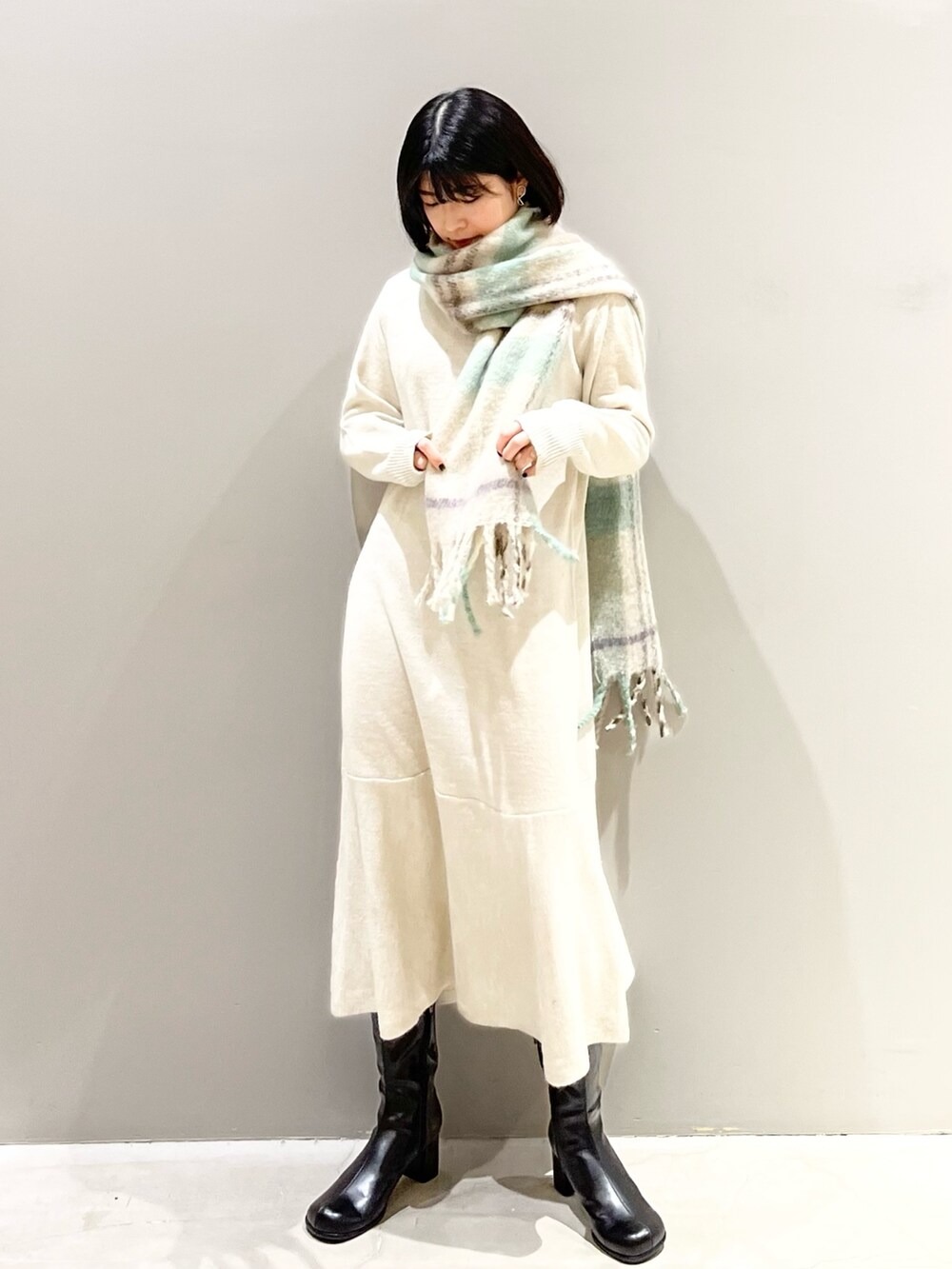 ブラック系のブーツ、ベージュ系のワンピース、ベージュ系のストール/ショールを着用したレディースの冬コーディネートの2枚目の写真