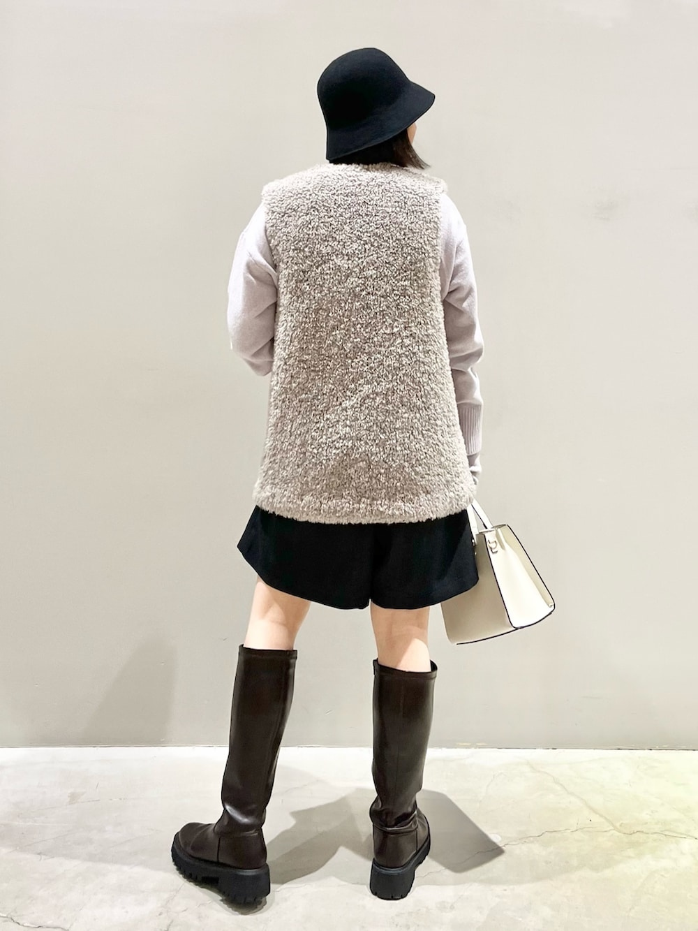 ブラウン系のブーツ、ホワイト系のショルダーバッグ、ブラック系のパンツを着用したレディースの冬コーディネートの3枚目の写真