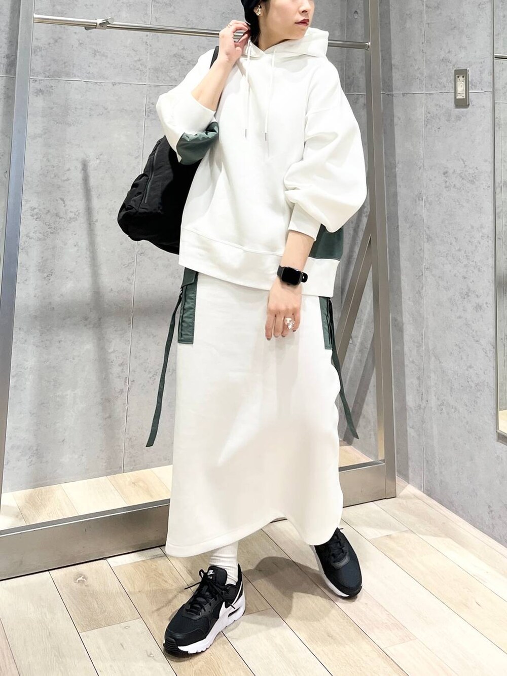 ブラック系のショルダーバッグ、ホワイト系のスカート、ホワイト系のパーカーを着用したレディースの冬コーディネートの6枚目の写真