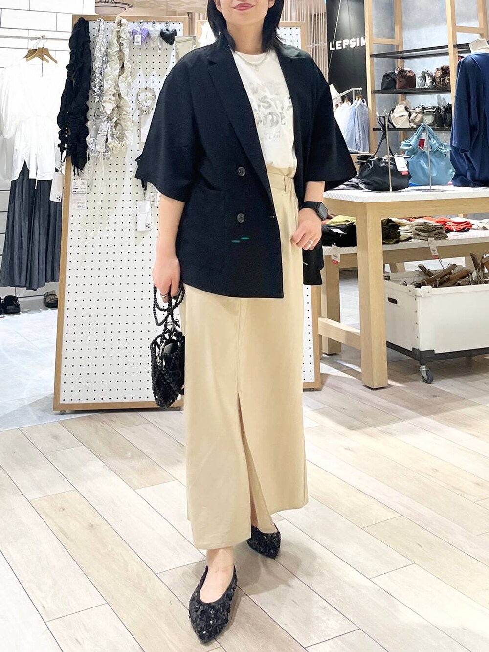 ブラック系のテーラードジャケット、ブラック系のショルダーバッグ、ホワイト系のTシャツ/カットソーを着用したレディースの夏コーディネートの2枚目の写真