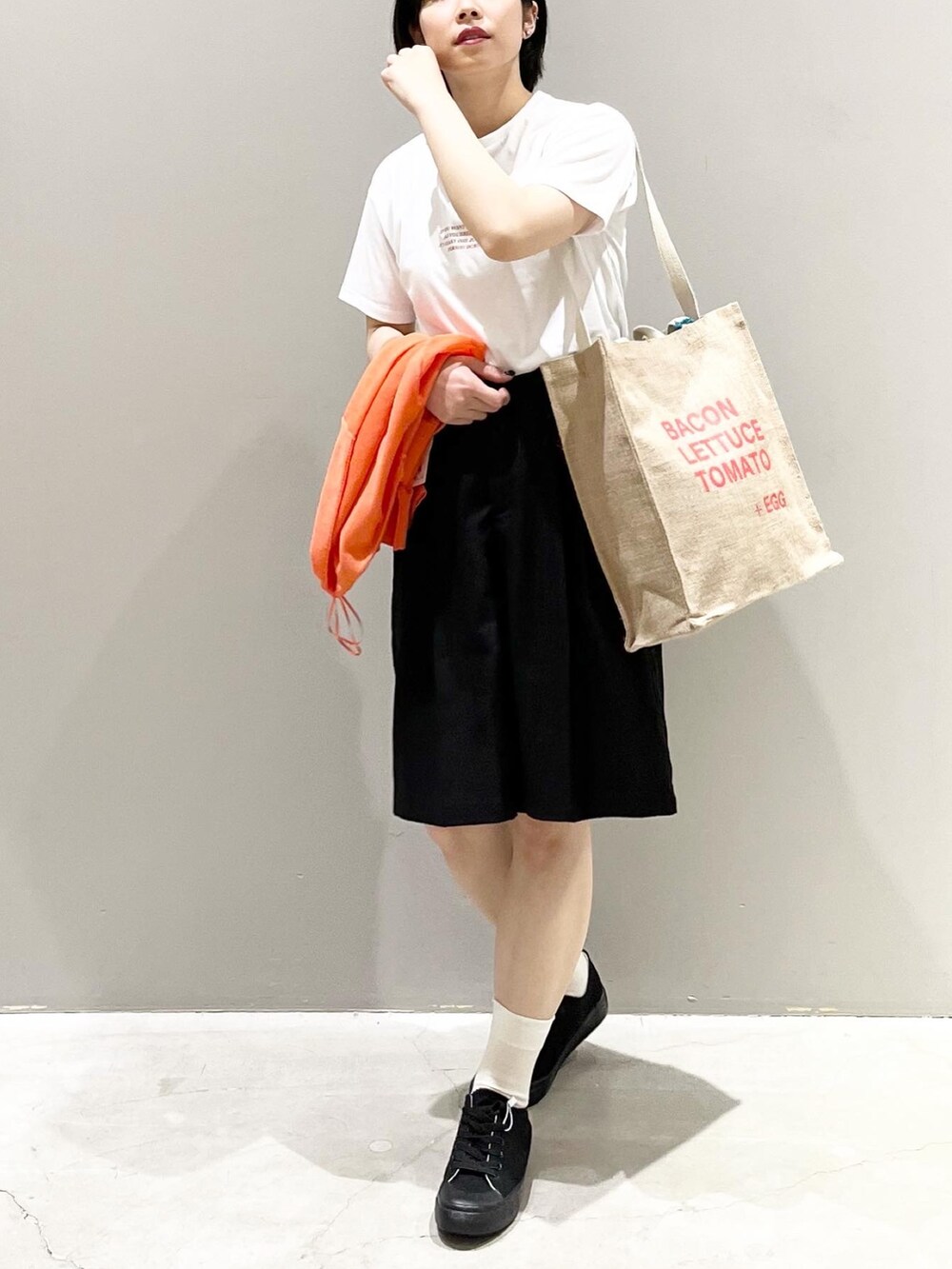 ブラック系のその他パンツ、ブラック系のスニーカー、オレンジ系のトートバッグを着用したレディースの夏コーディネートの3枚目の写真