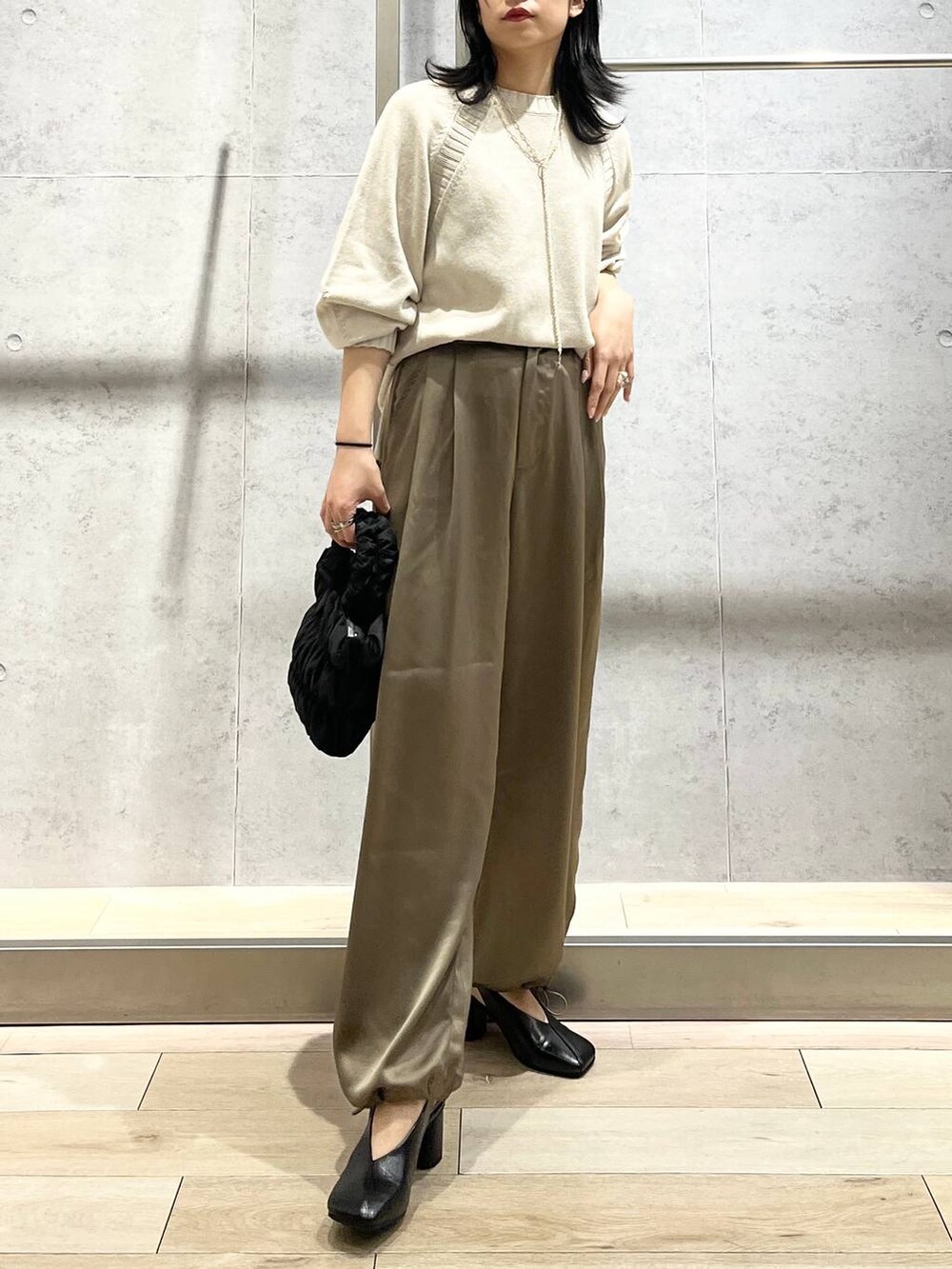 ブラック系のショルダーバッグ、ブラック系のパンプス、イエロー系のその他パンツを着用したレディースの冬コーディネートの7枚目の写真