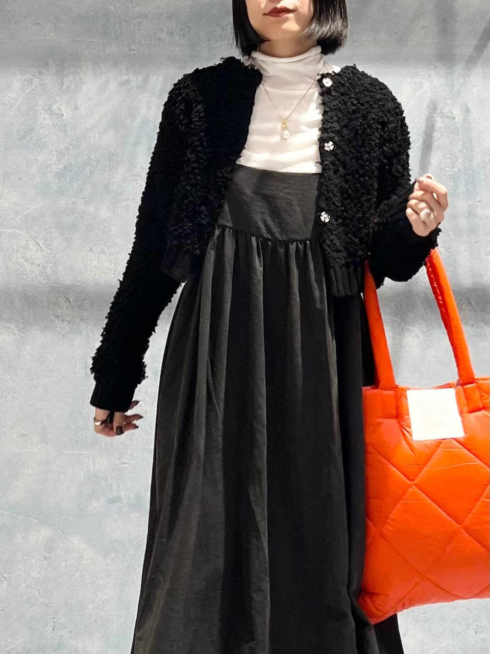 オレンジ系のトートバッグ、グレー系のワンピース、ブラック系のブーツを着用したレディースの冬コーディネートの6枚目の写真