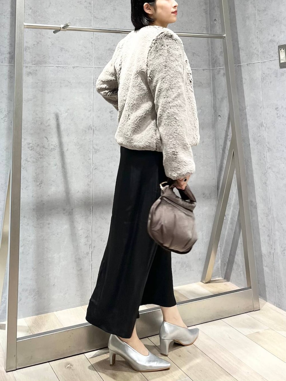 シルバー系のパンプス、ブラウン系のハンドバッグ、ベージュ系のノーカラーコートを着用したレディースの秋コーディネートの8枚目の写真