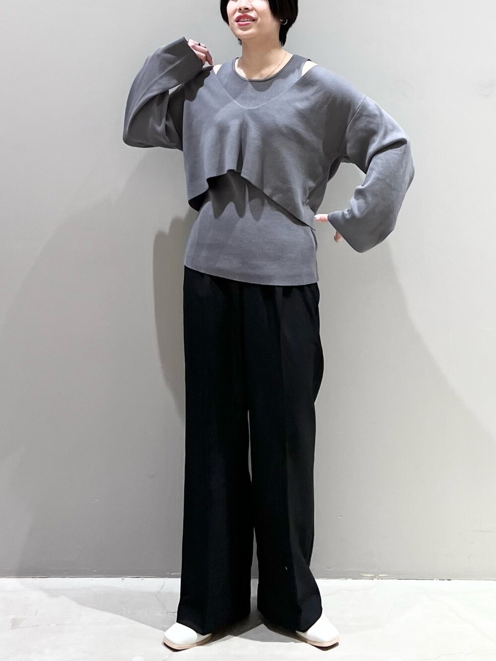グレー系のニット/セーター、ブラック系のパンツ、ホワイト系のシューズを着用したレディースの春コーディネートの7枚目の写真
