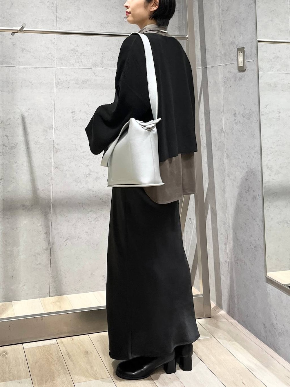 ブラック系のスカート、ブラック系のニット/セーター、グレー系のシャツ/ブラウスを着用したレディースの秋コーディネートの4枚目の写真