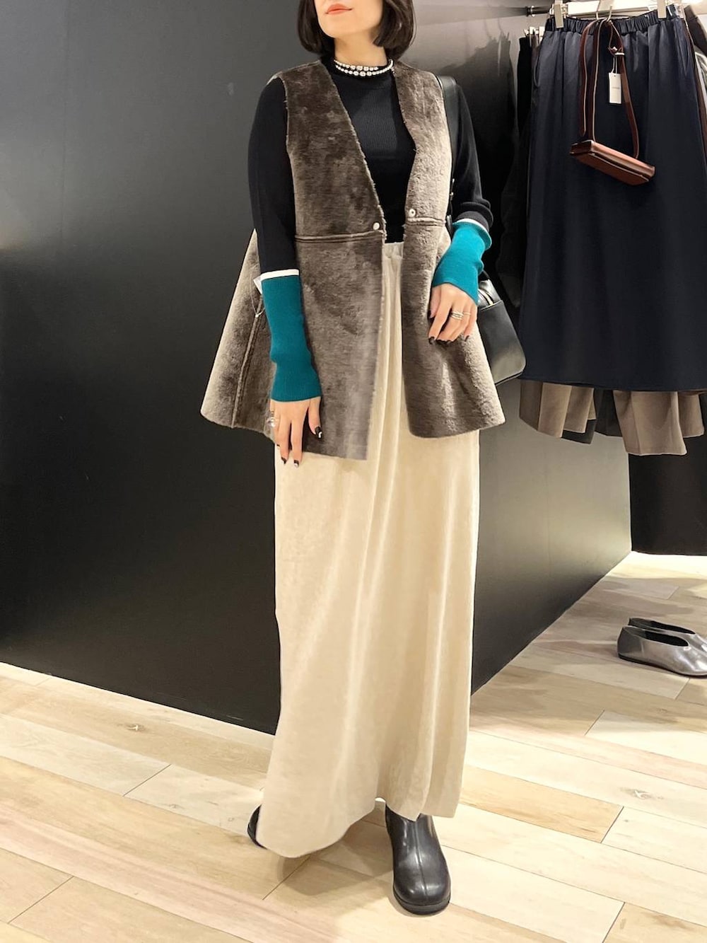 ブラック系のニット/セーター、ブラック系のブーツ、ブラック系のショルダーバッグを着用したレディースの秋コーディネートの2枚目の写真