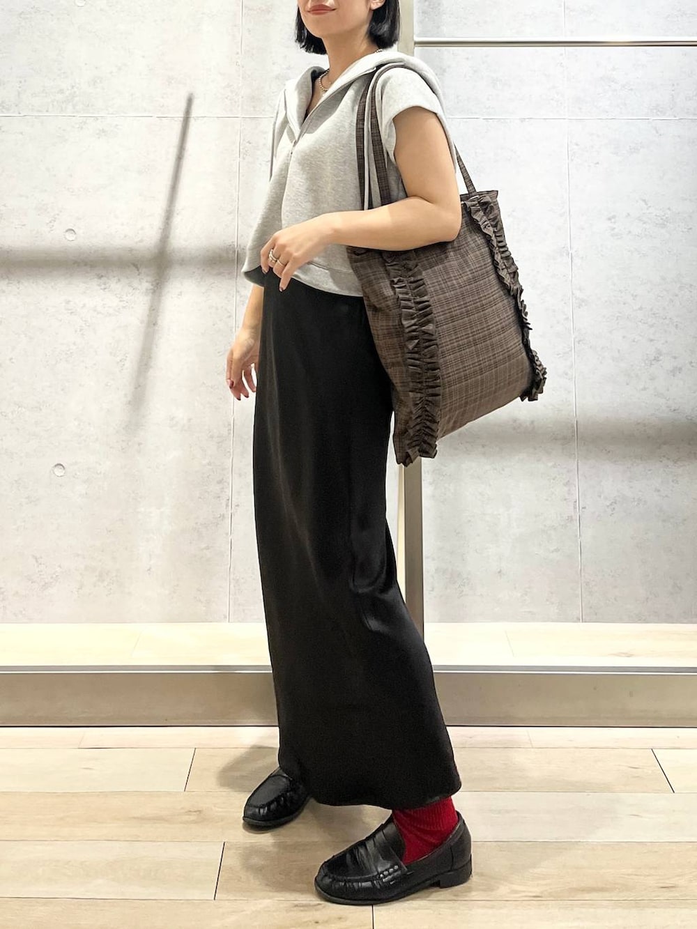 ブラック系のスカート、ブラウン系のトートバッグ、グレー系のベストを着用したレディースの秋コーディネートの3枚目の写真