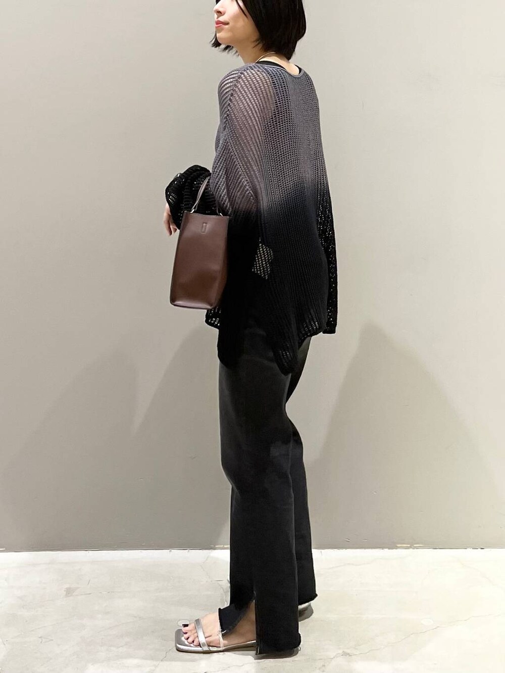 ブラック系のニット/セーター、シルバー系のサンダル、ブラック系のデニムパンツを着用したレディースの夏コーディネートの4枚目の写真