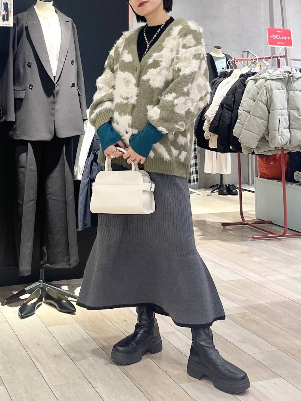 ブラック系のニット/セーター、ブラック系のスカート、ブラック系のブーツを着用したレディースの冬コーディネートの2枚目の写真