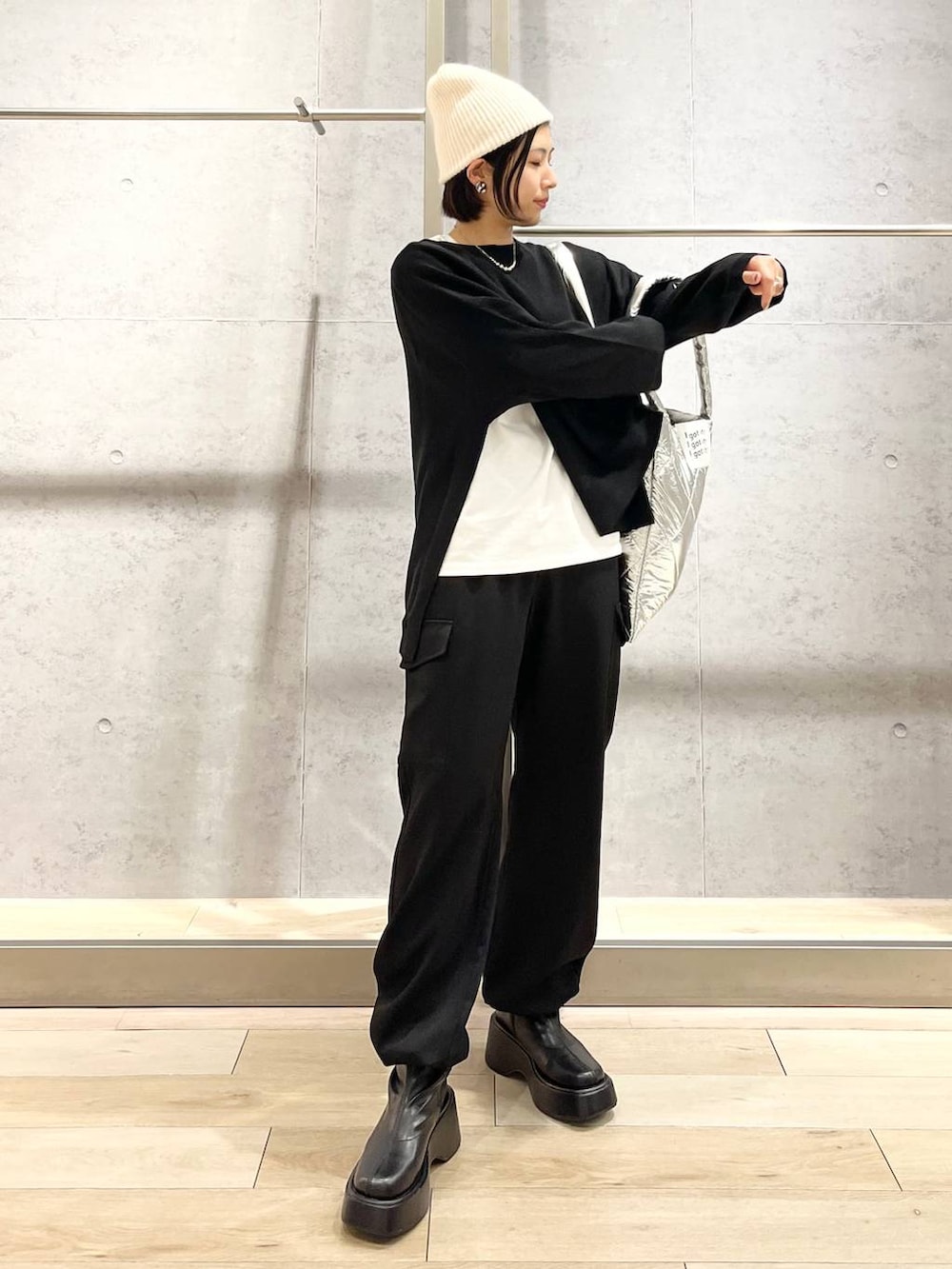 ブラック系のニット/セーター、ホワイト系のTシャツ/カットソー、ブラック系のブーツを着用したレディースの秋コーディネートの3枚目の写真