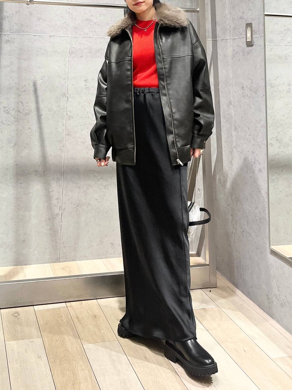 ブラック系のブーツ、オレンジ系のニット/セーター、ブラック系のスカートを着用したレディースの冬コーディネートの2枚目の写真