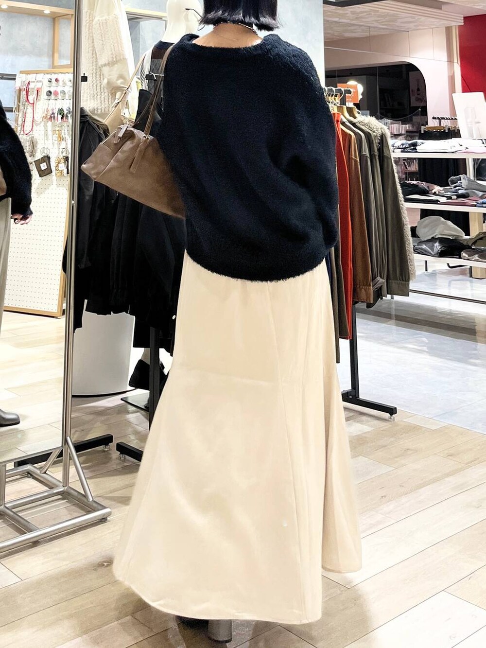 ブラウン系のボストンバッグ、ブラック系のスカート、その他のブーツを着用したレディースの秋コーディネートの4枚目の写真