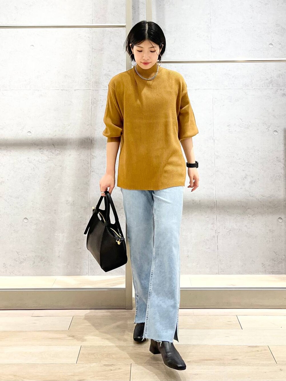 ブラウン系のニット/セーター、ブルー系のデニムパンツ、ベージュ系のショルダーバッグを着用したレディースの秋コーディネートの2枚目の写真