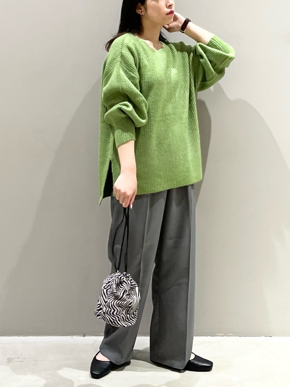 グリーン系のニット/セーター、ブラック系のパンプス、グレー系のパンツを着用したレディースの秋コーディネートの3枚目の写真