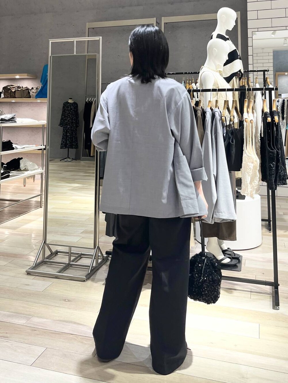 グレー系のチノパンツ、ブラック系のスニーカー、ホワイト系のキャミソールを着用したレディースの秋コーディネートの2枚目の写真