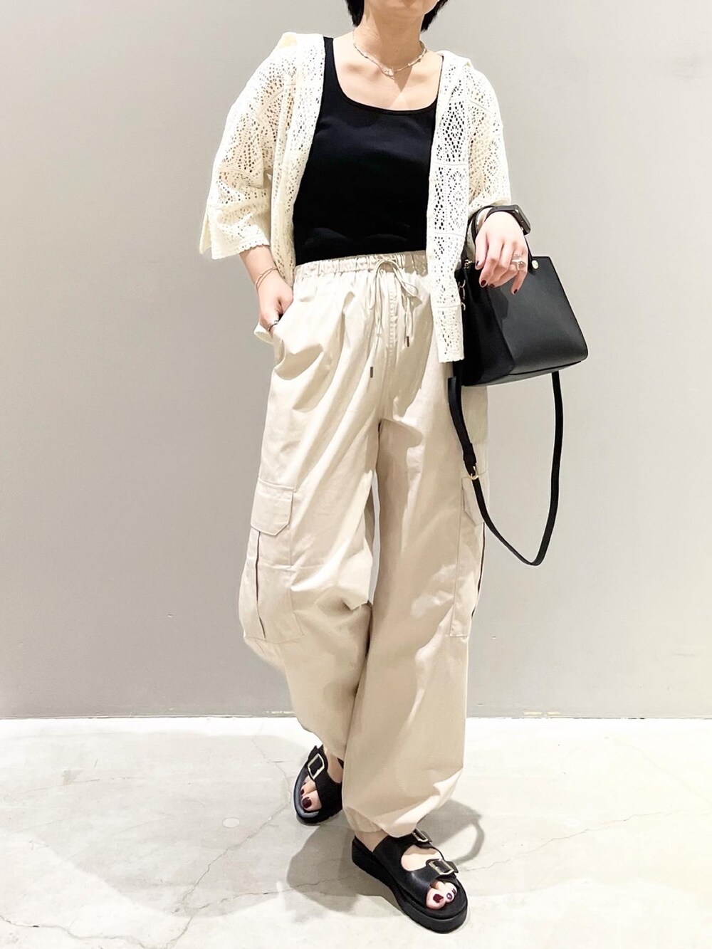 グリーン系のパンツ、ブラック系のサンダル、ブラック系のショルダーバッグを着用したレディースの春コーディネートの2枚目の写真