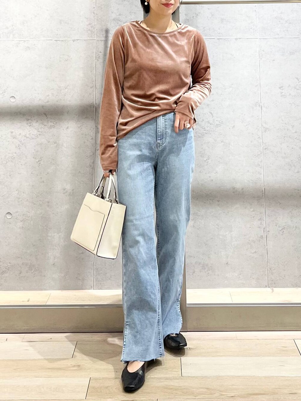 ブラック系のパンプス、ブルー系のデニムパンツ、ホワイト系のショルダーバッグを着用したレディースの秋コーディネートの9枚目の写真