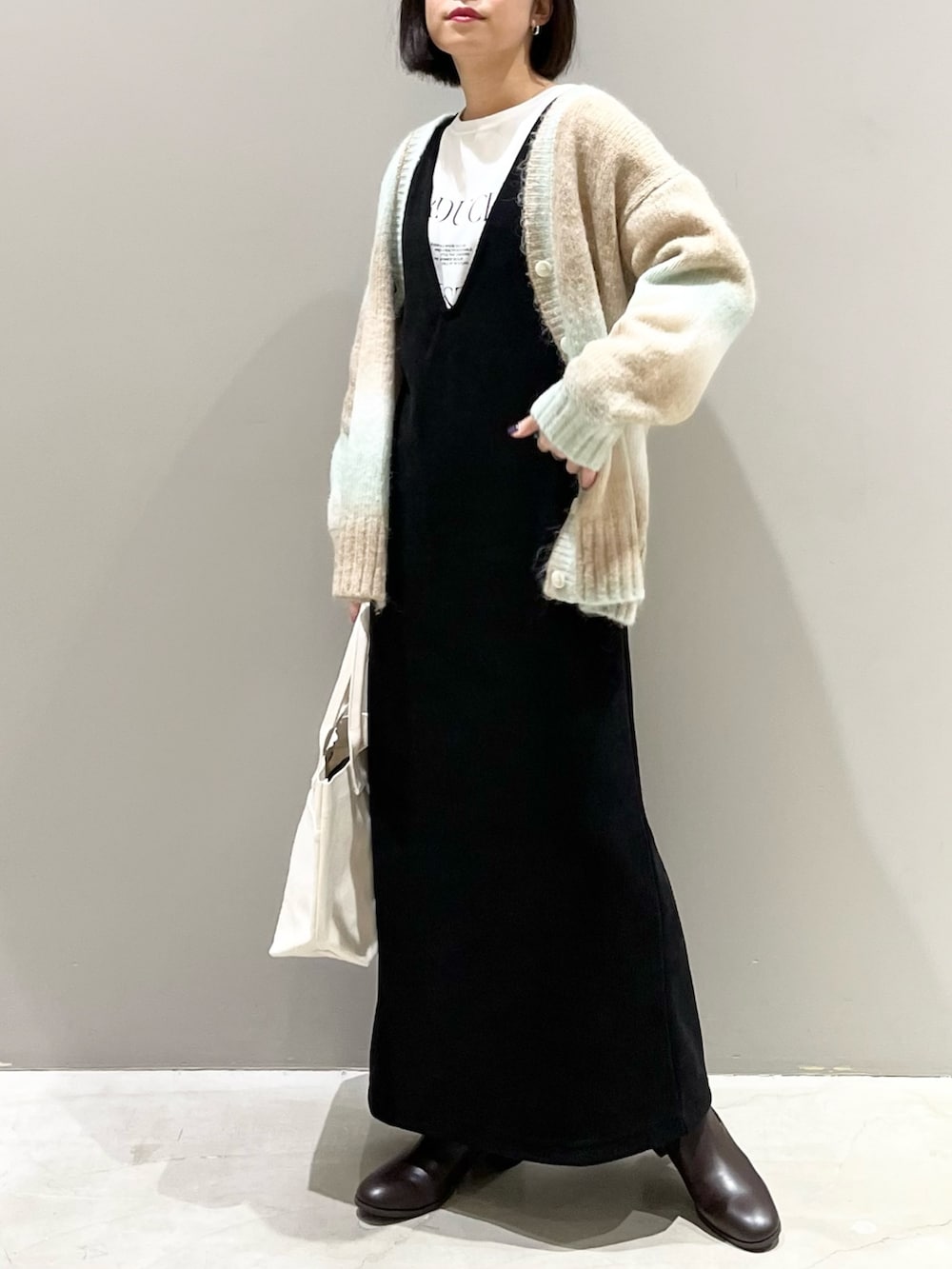 ブラック系のワンピース、グリーン系のカーディガン/ボレロ、ホワイト系のTシャツ/カットソーを着用したレディースの冬コーディネートの2枚目の写真