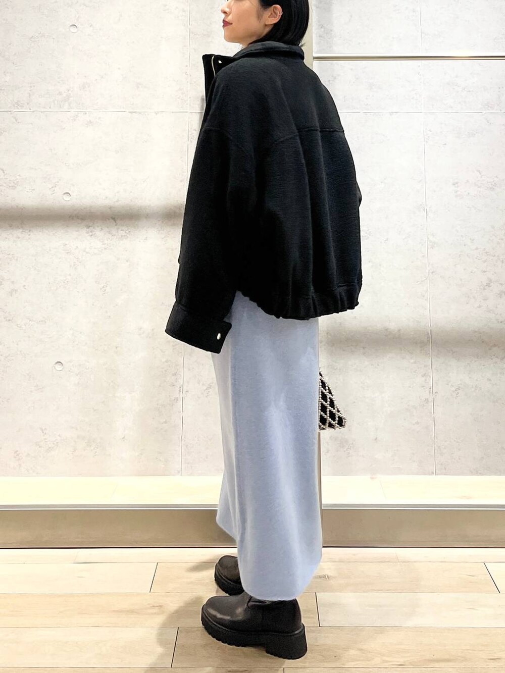 ブラック系のブルゾン、ブルー系のワンピース、ブラック系のブーツを着用したレディースの秋コーディネートの5枚目の写真