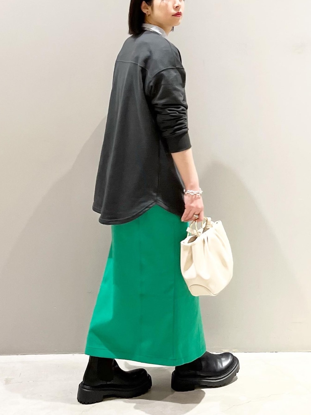 グレー系のTシャツ/カットソー、グリーン系のスカート、ブラック系のブーツを着用したレディースの春コーディネートの2枚目の写真
