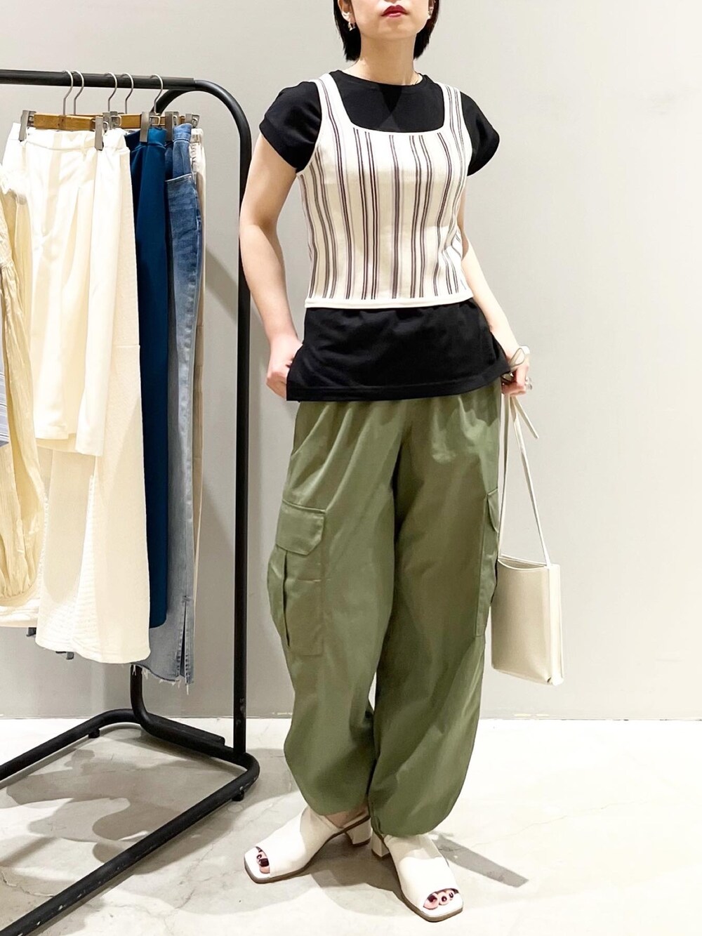 ベージュ系のタンクトップ、ブラック系のTシャツ/カットソー、グリーン系のパンツを着用したレディースの夏コーディネートの2枚目の写真