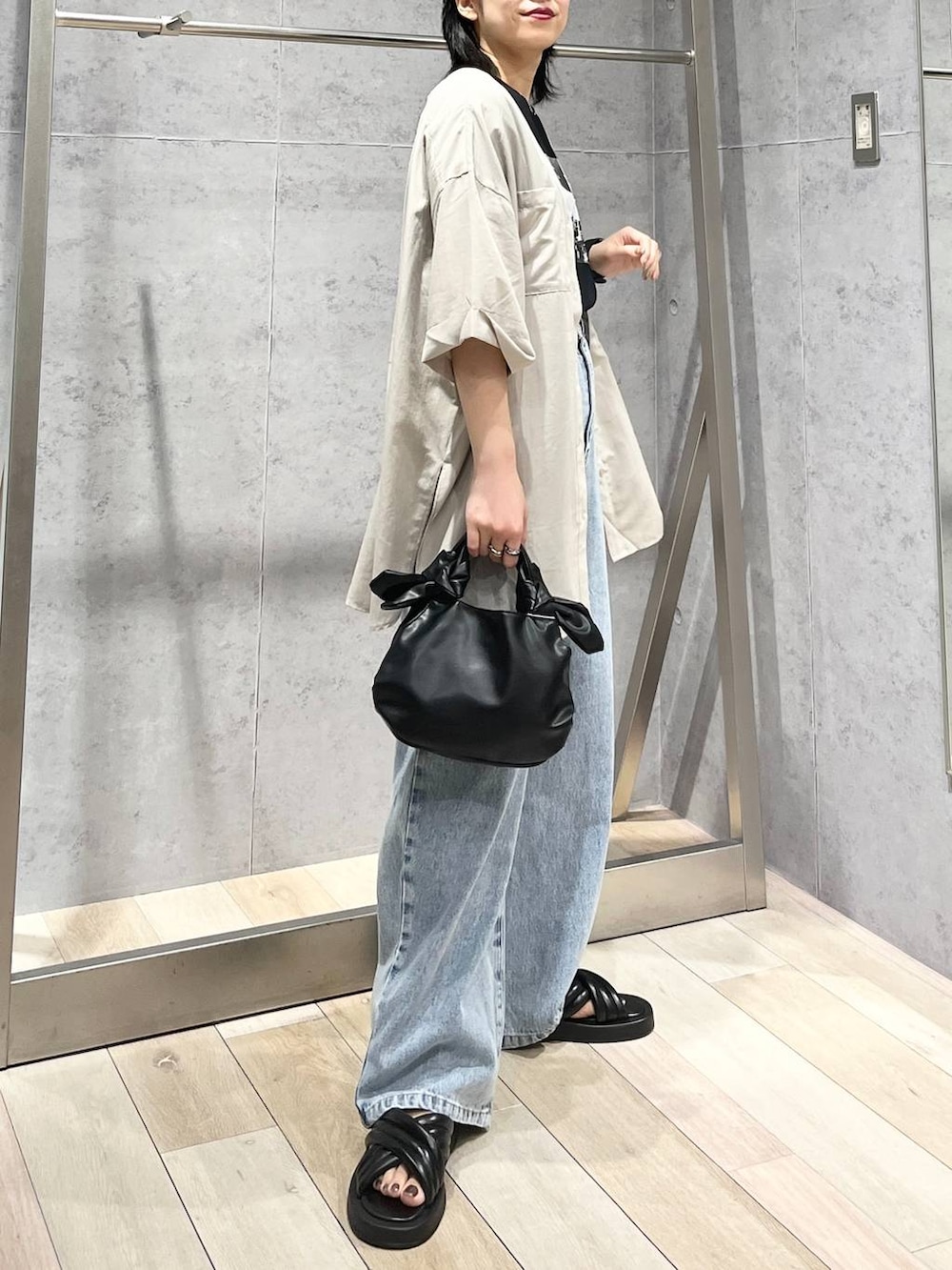 ブラック系のTシャツ/カットソー、ブラック系のサンダル、ブルー系のデニムパンツを着用したレディースの夏コーディネートの6枚目の写真