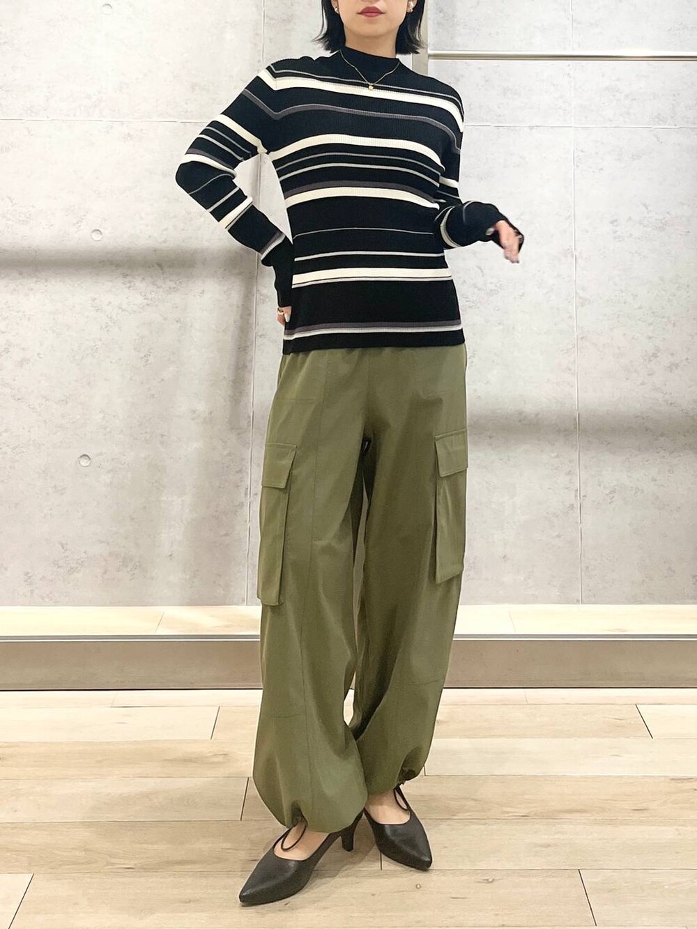 グレー系のベスト、ブラック系のハンドバッグ、グリーン系のカーゴパンツを着用したレディースの冬コーディネートの2枚目の写真