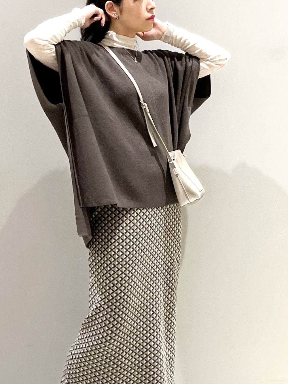 ブラウン系のスカート、ブラック系のブーツ、ブラウン系のニット/セーターを着用したレディースの秋コーディネートの3枚目の写真