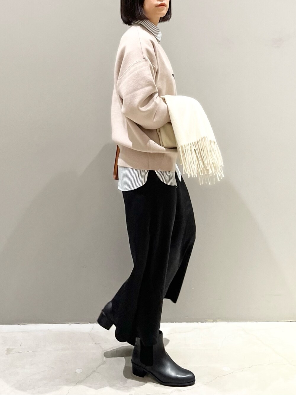 ブラック系のスカート、ブラック系のブーツ、ブラウン系のショルダーバッグを着用したレディースの冬コーディネートの2枚目の写真