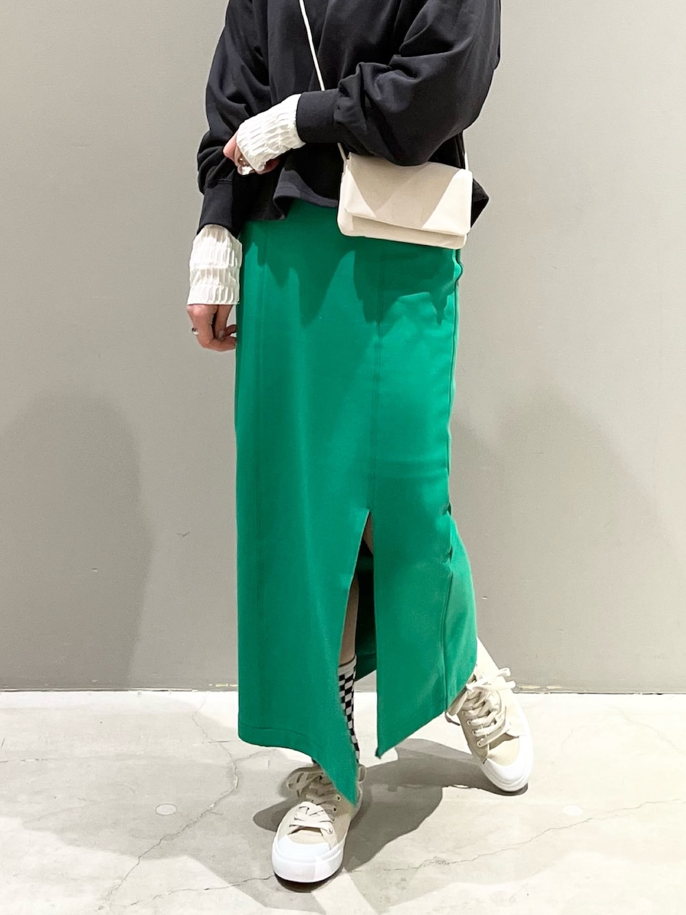 グリーン系のスカート、ベージュ系のスニーカー、ホワイト系のショルダーバッグを着用したレディースの春コーディネートの5枚目の写真