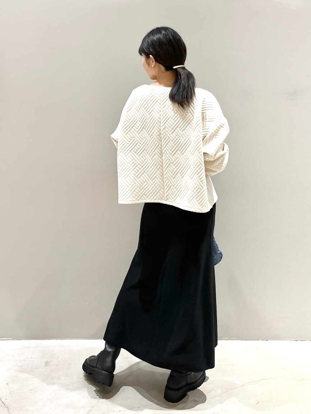 ブラック系のブーツ、ブラック系のスカート、ブルー系のショルダーバッグを着用したレディースの秋コーディネートの3枚目の写真