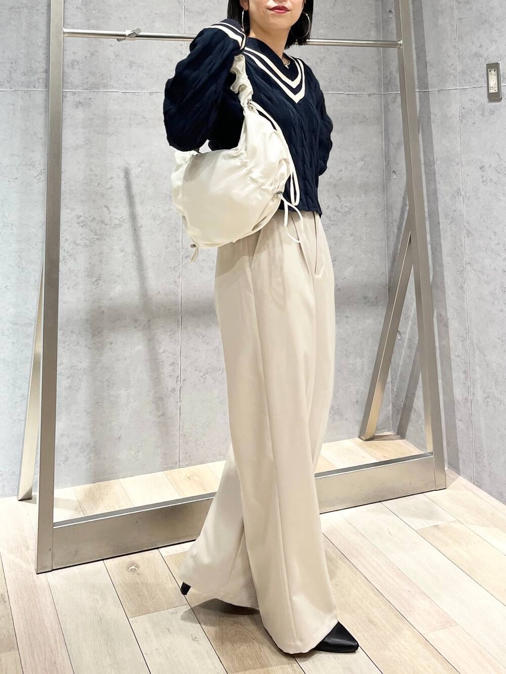 ブルー系のニット/セーター、ホワイト系のショルダーバッグ、ブラック系のパンプスを着用したレディースの冬コーディネートの3枚目の写真