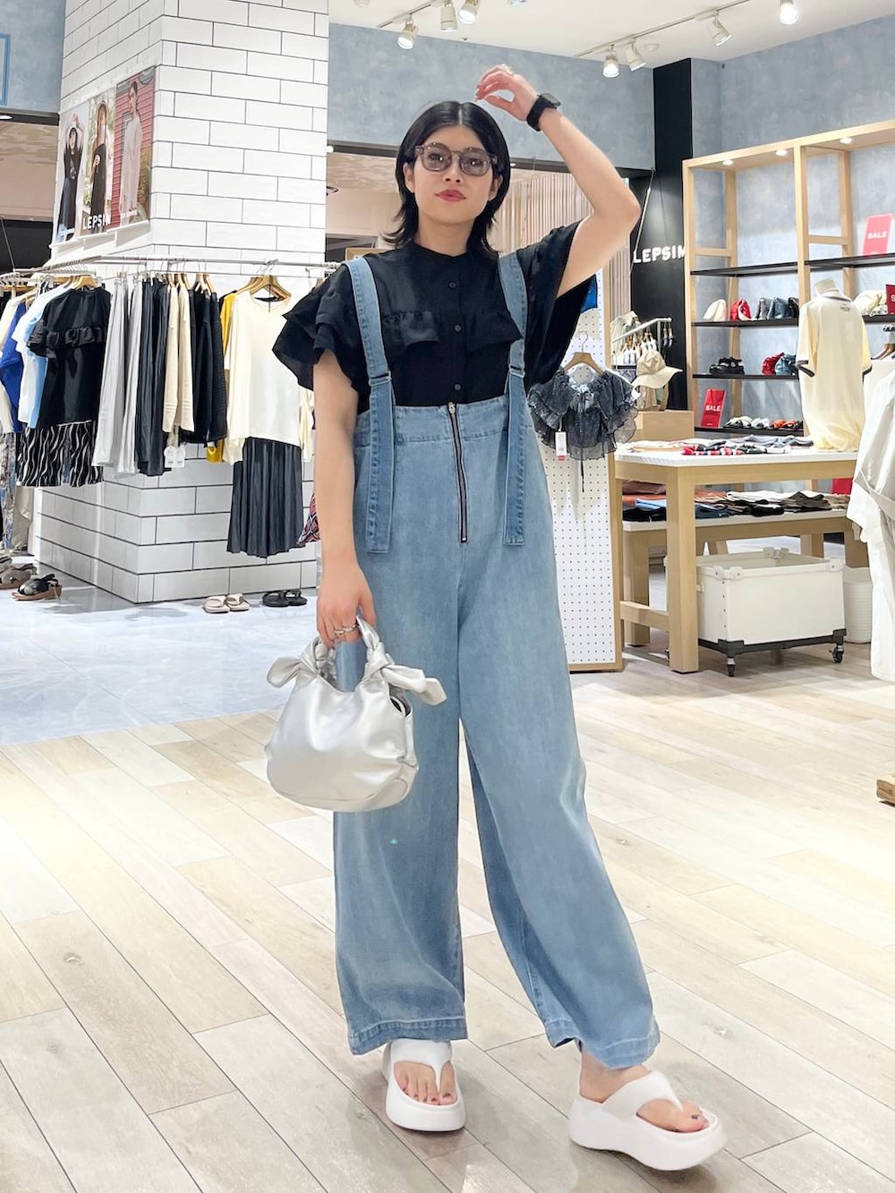 ホワイト系のサンダル、ブルー系のデニムパンツ、シルバー系のショルダーバッグを着用したレディースの夏コーディネートの2枚目の写真