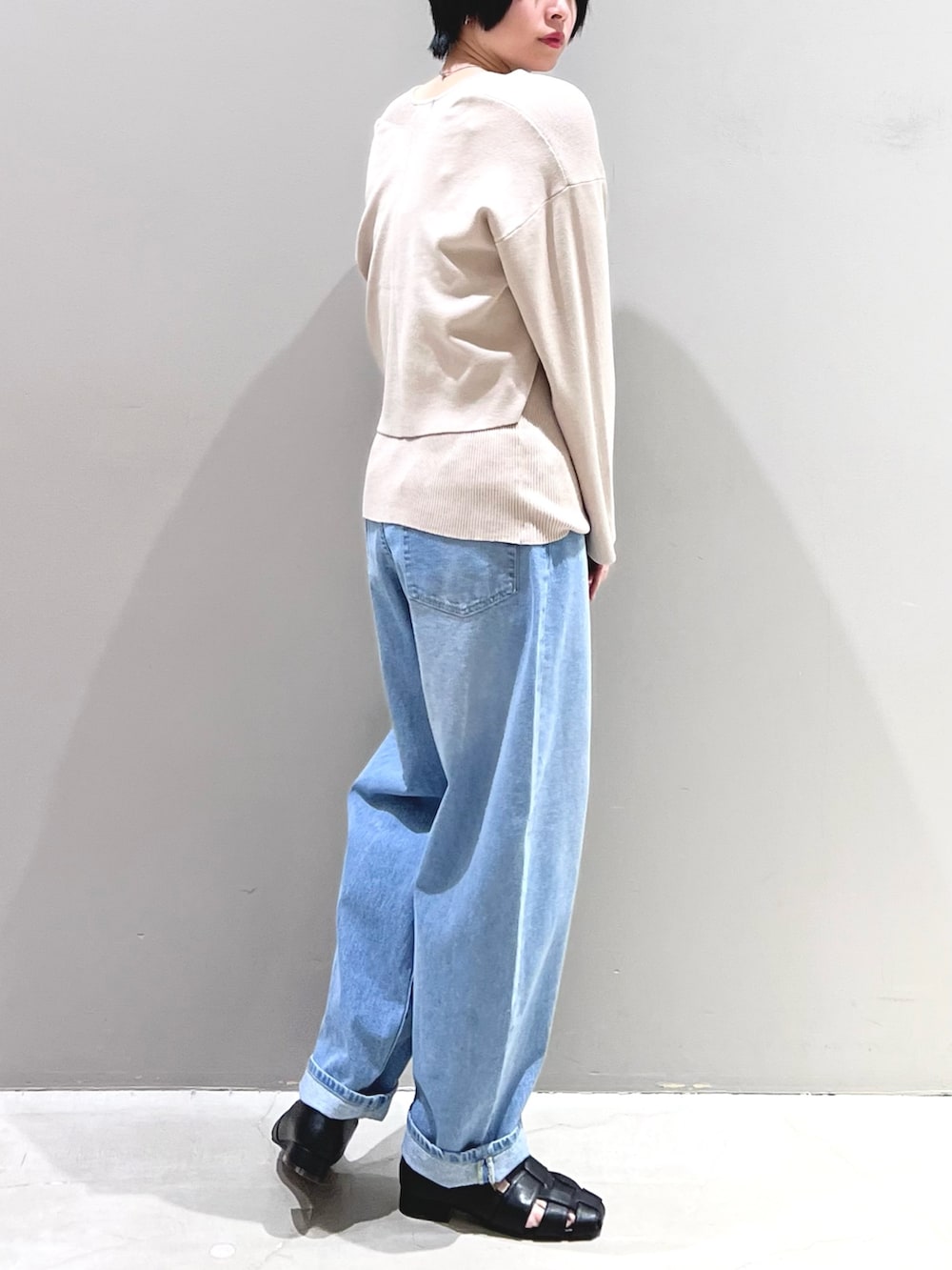 ブルー系のデニムパンツ、ブラック系のシューズ、ベージュ系のニット/セーターを着用したレディースの春コーディネートの3枚目の写真