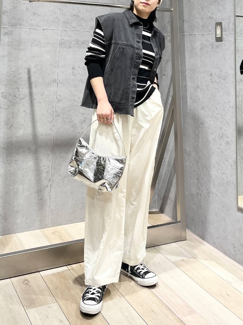 シルバー系のハンドバッグ、グレー系のベスト、ホワイト系のその他パンツを着用したレディースの冬コーディネートの2枚目の写真