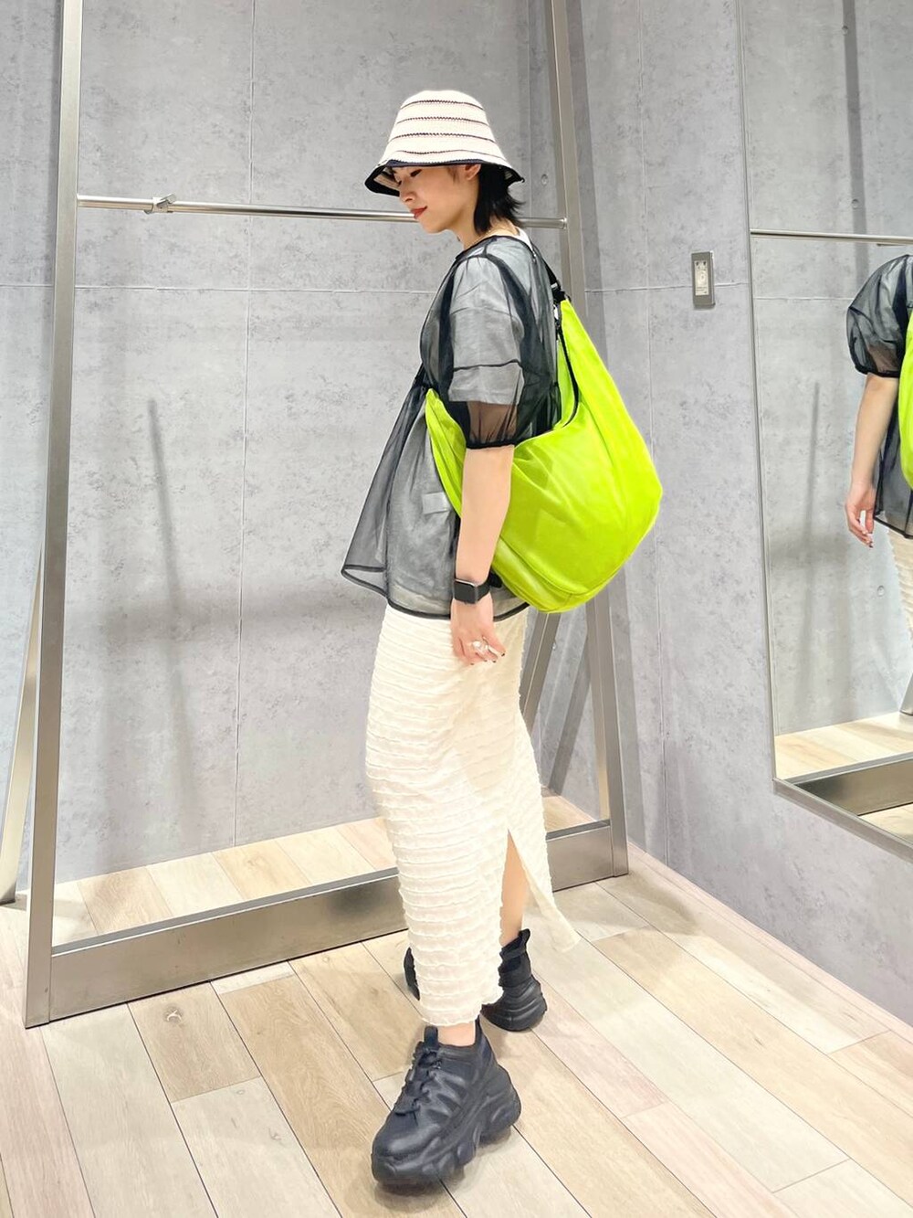 ブラック系のスニーカー、ホワイト系のスカート、グリーン系のショルダーバッグを着用したレディースの春コーディネートの6枚目の写真