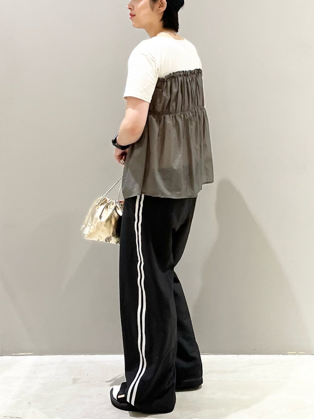 ブラック系のパンツ、ブラック系のサンダル、ゴールド系のハンドバッグを着用したレディースの秋コーディネートの5枚目の写真