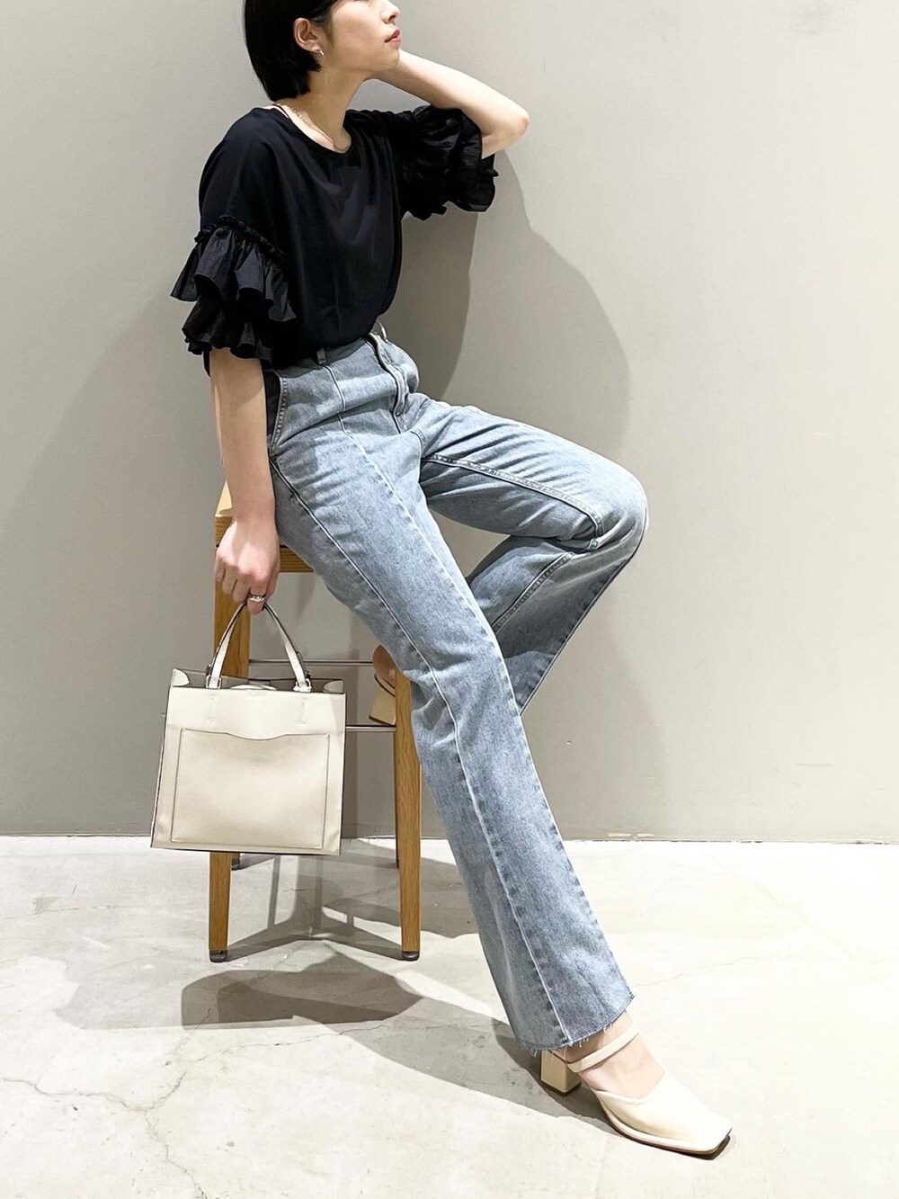 ブルー系のデニムパンツ、ホワイト系のショルダーバッグ、ホワイト系のパンプスを着用したレディースの夏コーディネートの6枚目の写真