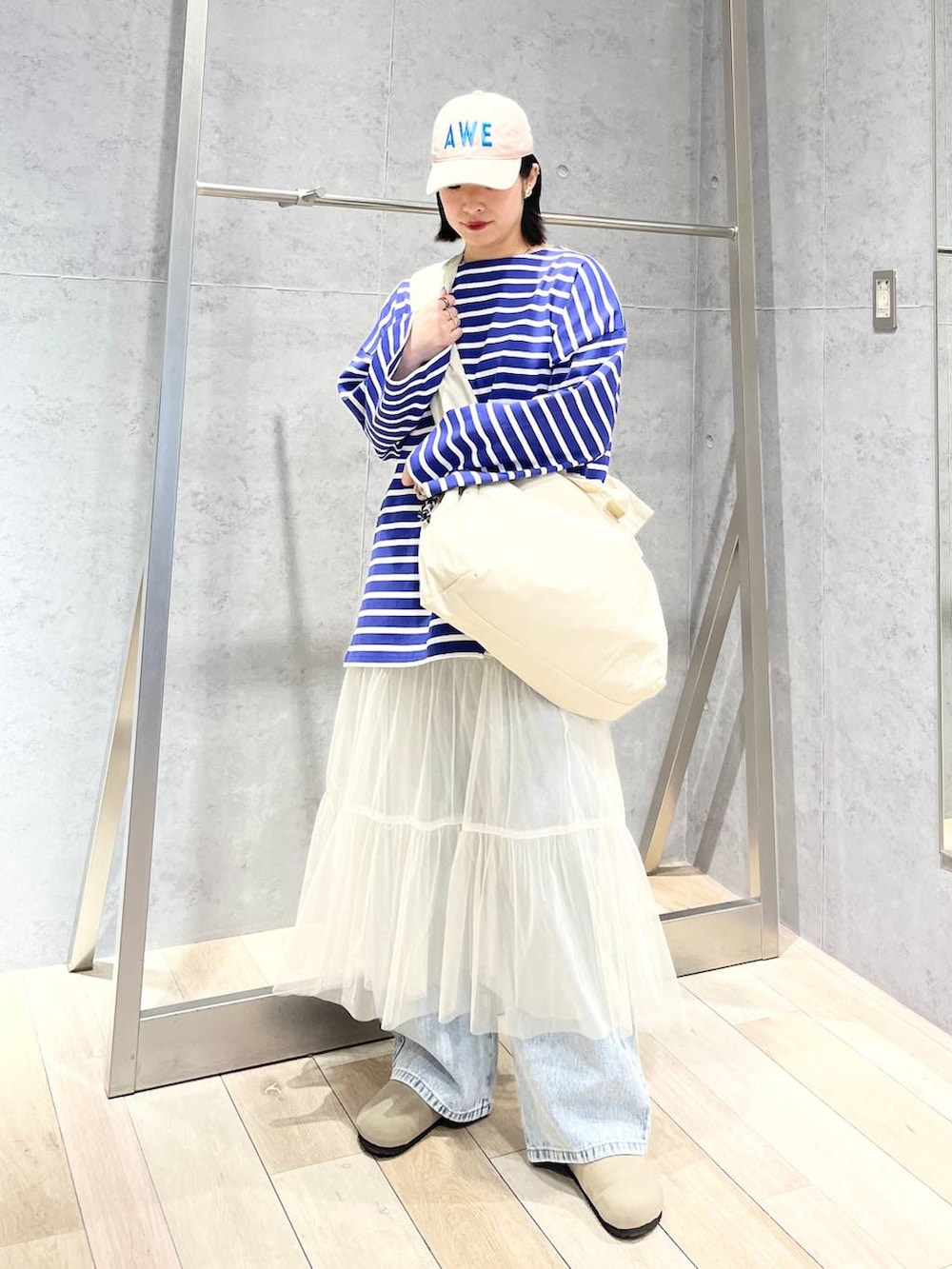 ホワイト系のスカート、パープル系のTシャツ/カットソー、ブルー系のデニムパンツを着用したレディースの冬コーディネートの2枚目の写真