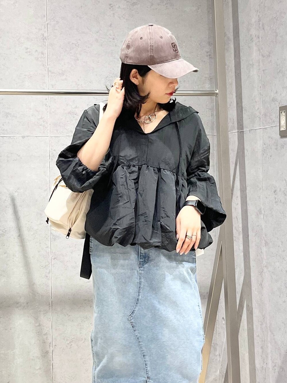 ホワイト系のショルダーバッグ、ブルー系のデニムスカート、ブラウン系のキャップを着用したレディースの冬コーディネートの2枚目の写真