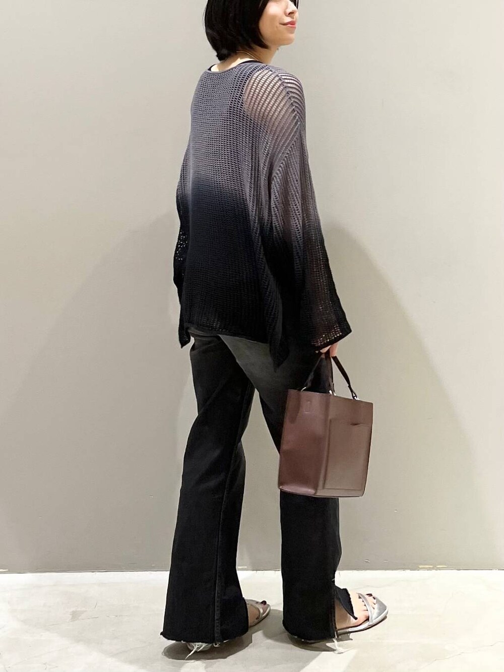 ブラック系のニット/セーター、シルバー系のサンダル、ブラック系のデニムパンツを着用したレディースの夏コーディネートの8枚目の写真